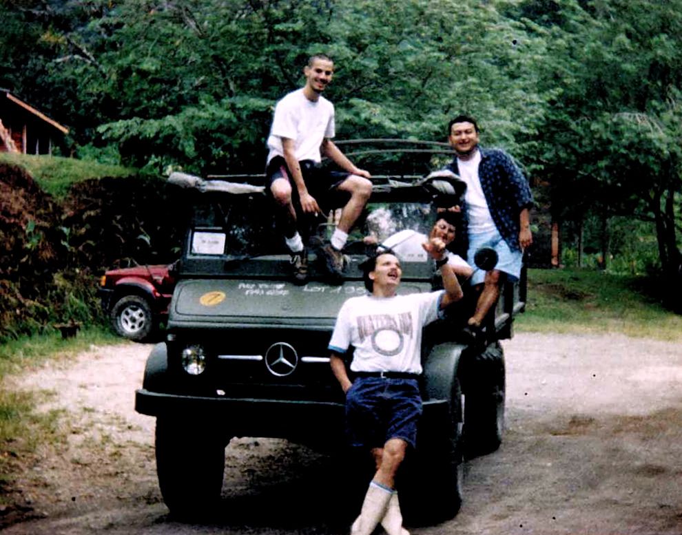 Archivfoto: eine Gruppe junger Leute um einen alten Unimog auf einem Feldweg
