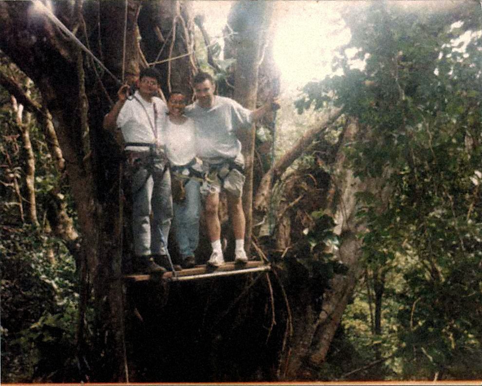 Archivfoto: drei Personen mit Gurt auf einer kleinen Holzplattform in einem Baum